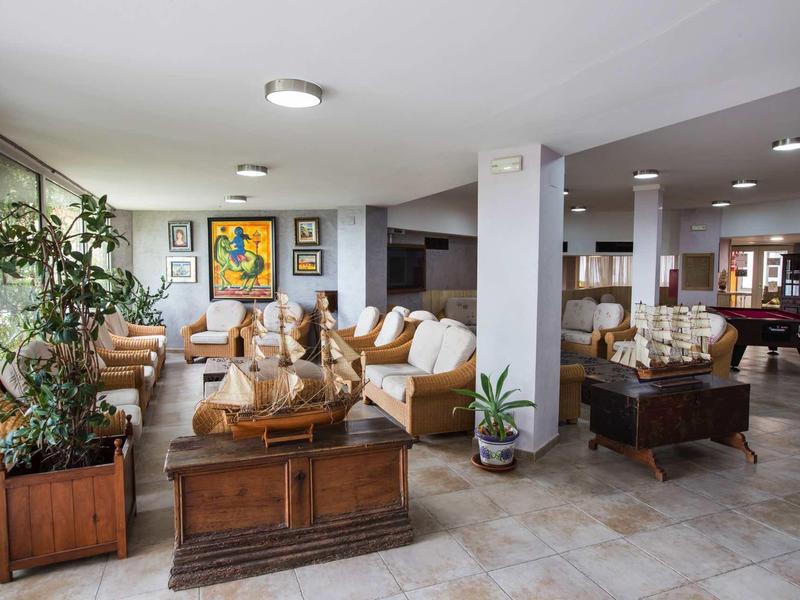 Spacious hotel lobby with sofas, plants, art, and a pool table in a cozy setting.