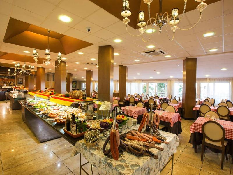 Large dining area with buffet tables and round pink-covered chairs under bright ceiling lights.