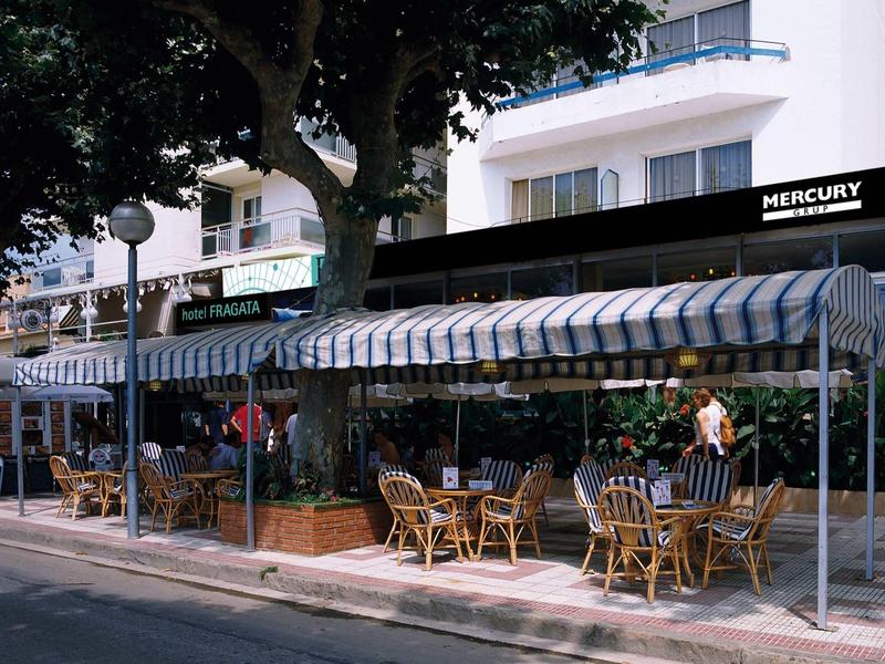 Na zewnątrz hotelu z zadaszonym tarasem i miejscami do siedzenia pod drzewami przy ulicy.