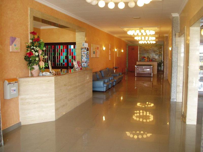 Jasna lobby hotelowa z recepcją, wygodnym miejscem do siedzenia i błyszczącą podłogą.