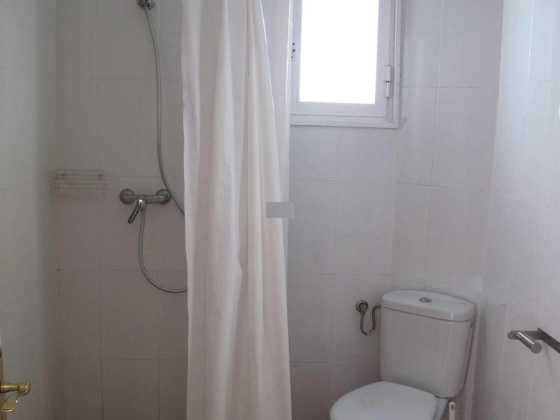 Mała łazienka z toaletą, zasłoną prysznicową i oknem.