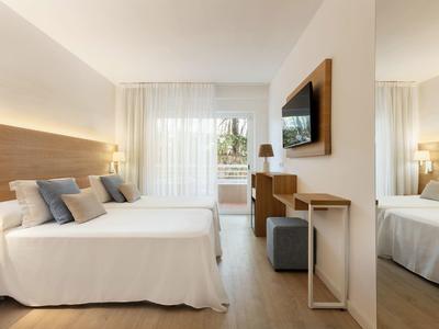 Modern eingerichtetes Schlafzimmer mit großem Bett, Holzverkleidung und heller Bodenterrasse.