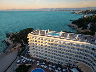 Hotel am Meer mit Poolbereich und Sonnenliegen, umgeben von Küste und klarem Wasser.