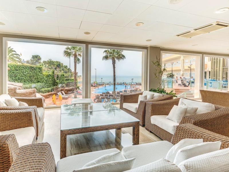 Helles Wohnzimmer mit weißen Sofas, Glas-Couchtisch und Meerblick durch große Fenster.