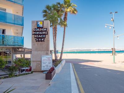 Tablica wejściowa hotelu Golden Donaire Beach z palmami i morzem w tle.