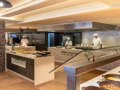 Nowoczesna kuchnia hotelowa z kucharzami przygotowującymi i prezentującymi jedzenie na bufecie.