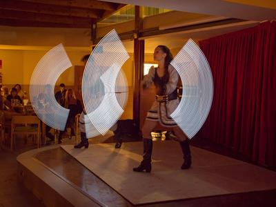 Dwie kobiety tańczą na scenie z czerwonym zasłoną w tle.