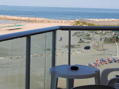 Balkon z stołem i krzesłami z widokiem na plażę i morze przy dobrej pogodzie.