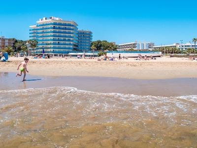 Plaża z piaskiem, ludźmi i budynkiem hotelu w tle pod czystym niebem