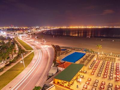 Plaża z kolorowymi parasolami i oświetlone miasto nocą przy morzu