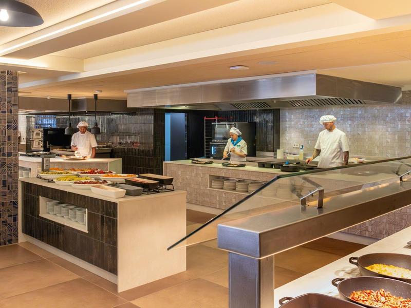 Nowoczesna kuchnia hotelowa z kucharzami przygotowującymi i prezentującymi jedzenie na bufecie.