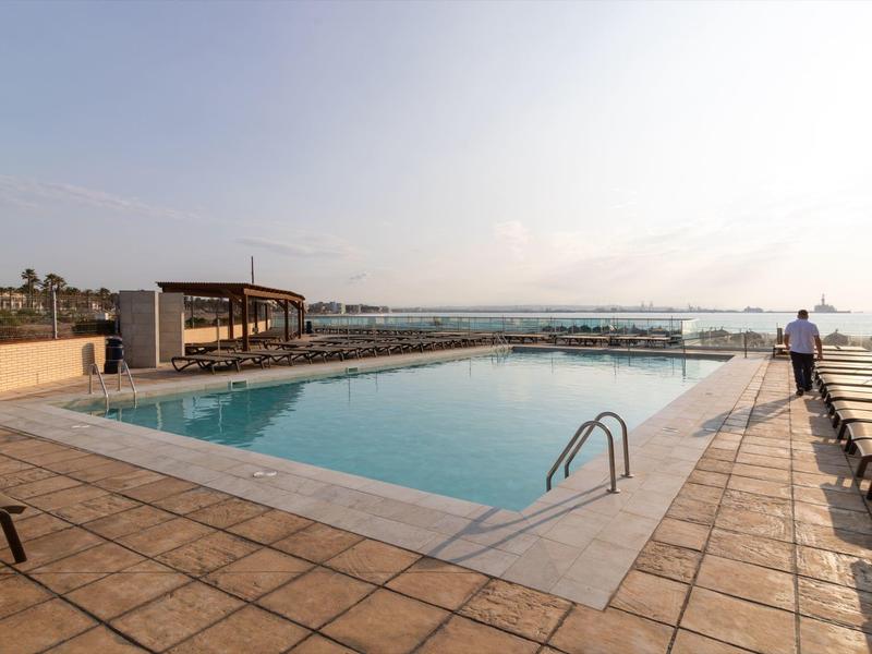 Basen na dachu z leżakami i widokiem na miasto pod czystym niebem