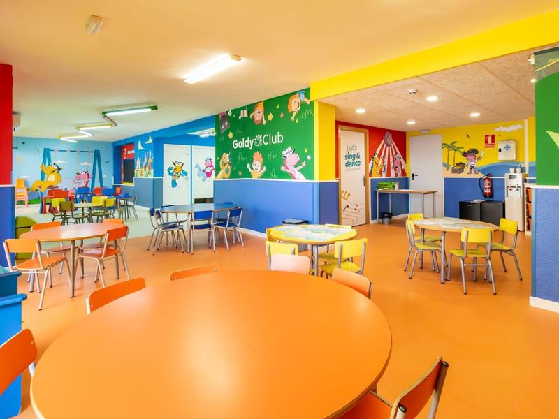 Kolorowy kącik zabaw dla dzieci z stołami, krzesłami i radosnymi dekoracjami w części hotelu.