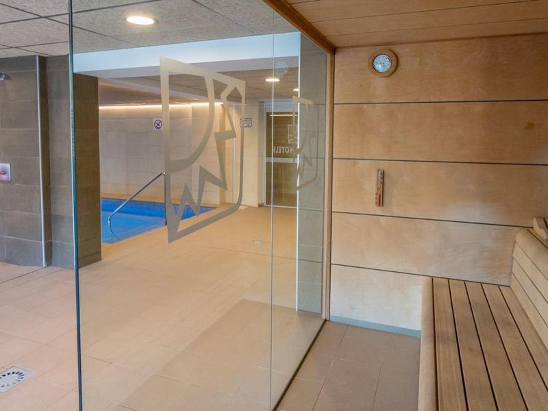 Nowoczesna sauna z drewnianą boazerią i panoramicznym oknem z widokiem na przyległy basen.