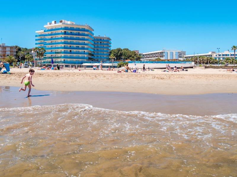 Plaża z piaskiem, ludźmi i budynkiem hotelu w tle pod czystym niebem