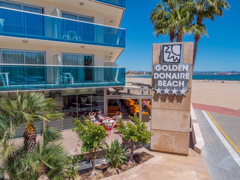 Nowoczesny kompleks hotelowy z tarasem i widokiem na morze na piaszczystej plaży w słoneczną pogodę.