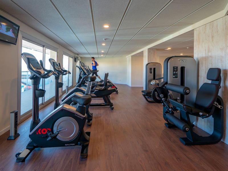 Nowoczesna siłownia z kilkoma maszynami do ćwiczeń i dużymi oknami.