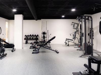 Innenansicht eines modernen Fitnessraums mit Trainingsgeräten und Hanteln in einem Hotel.