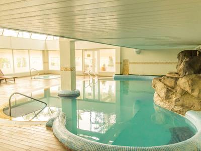 Innenpool mit Felsen, Holzdeck und großen Fenstern in einem Hotel.