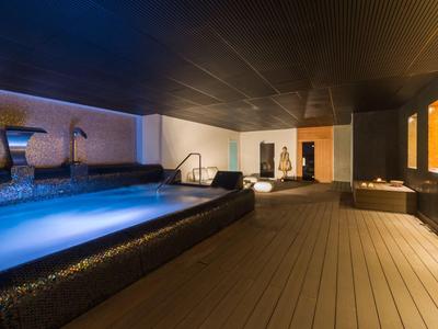 Moderner Innenpool mit entspannter Beleuchtung und Liegen in einem Hotel-Spa-Bereich.