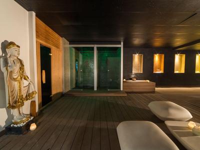 Moderner Spa-Bereich mit Holzterrasse, Liegen und stimmungsvoller Beleuchtung für Entspannung.