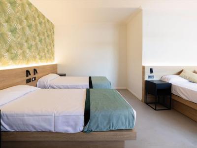 Helles Hotelzimmer mit zwei Einzelbetten und eine moderne grüne Wandgestaltung.