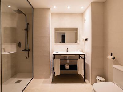 Modernes Badezimmer mit begehbarer Dusche, Waschbecken mit Spiegel und WC in neutralen Tönen.