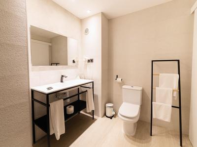 Modernes Badezimmer mit Waschbecken, Spiegel, Toilette und Handtüchern auf einem Ständer.