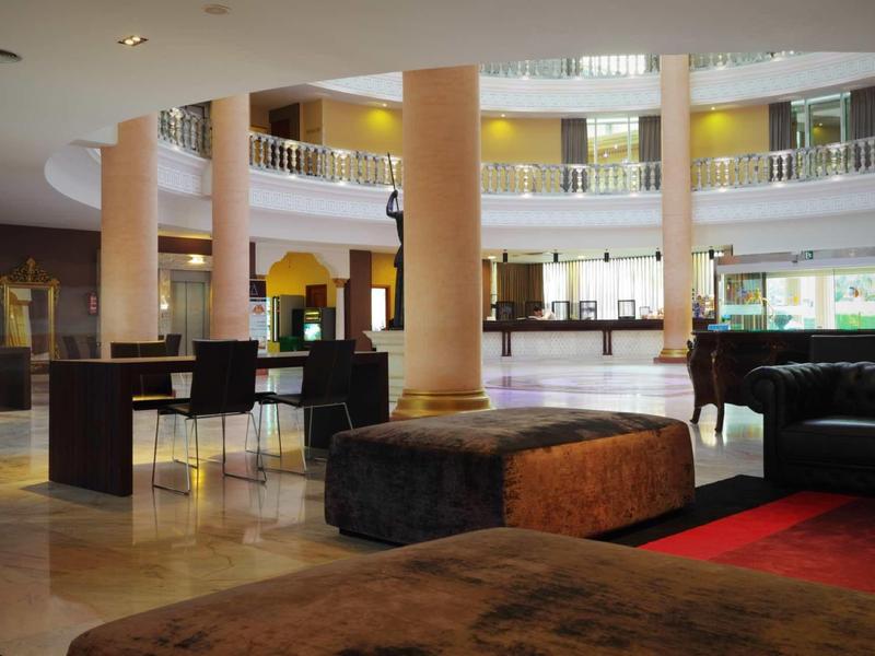 Spacious hotel lobby with columns, seating areas, and natural light windows.