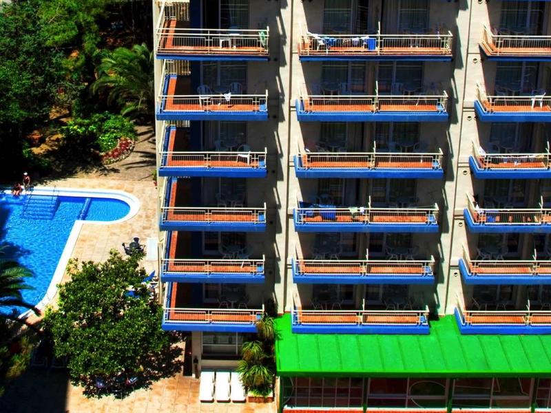 Hochhaus mit Balkonen neben Minigolfplatz mit grünem Kunstrasen und blauem Pool.