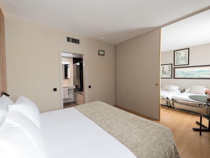 Camera da letto con letto grande e soggiorno adiacente in una camera d'hotel.