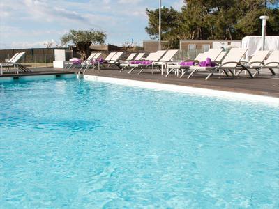 Piscina azzurra limpida con lettini sotto un cielo parzialmente nuvoloso in un ambiente rilassante all'aperto.