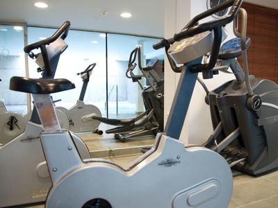 Cyclette moderne in una palestra luminosa con pannelli in legno alle pareti e grandi finestre.