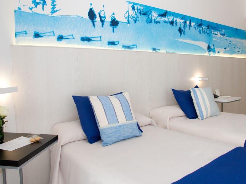 Camera doppia luminosa con cuscini blu e arte moderna sopra i letti.