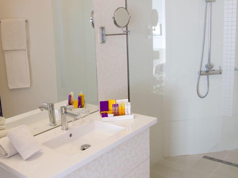Bagno bianco moderno con lavabo, specchio, articoli da toilette e doccia walk-in.