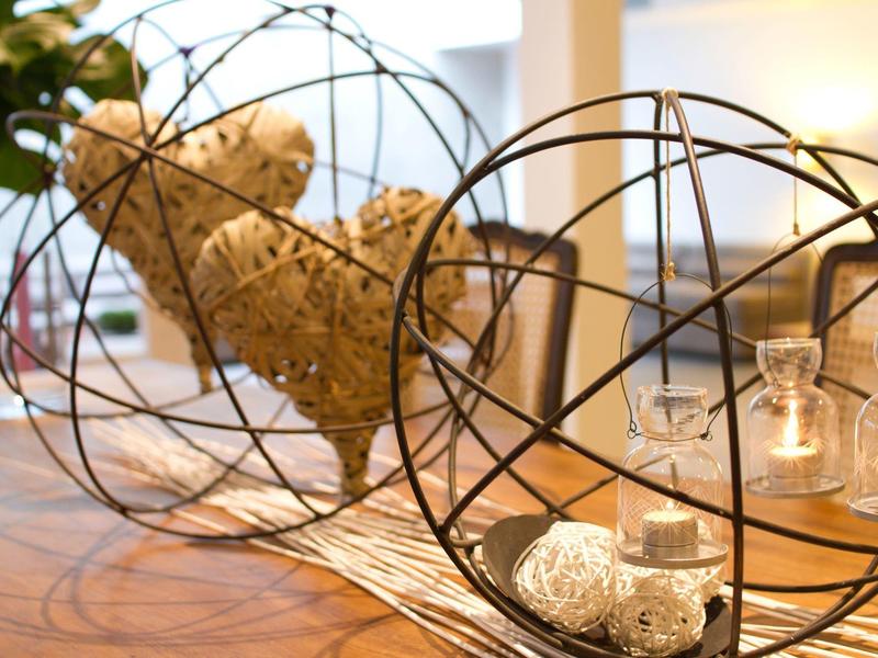 Interno con sculture a forma di globo in filo metallico che contengono oggetti decorativi su tavolo di legno.