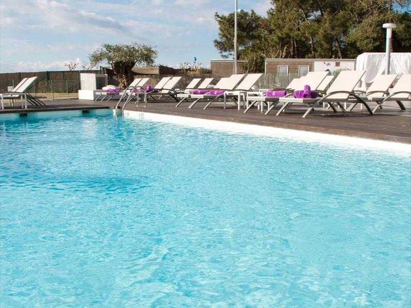 Piscina azzurra limpida con lettini sotto un cielo parzialmente nuvoloso in un ambiente rilassante all'aperto.