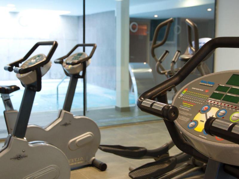 Palestra dell'hotel con cyclette e macchine ellittiche vicino a grandi finestre.