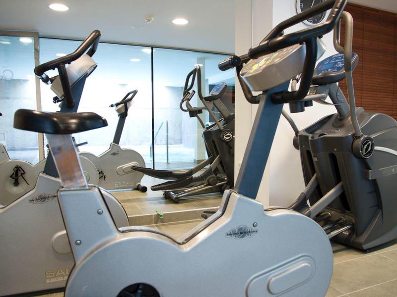 Cyclette moderne in una palestra luminosa con pannelli in legno alle pareti e grandi finestre.