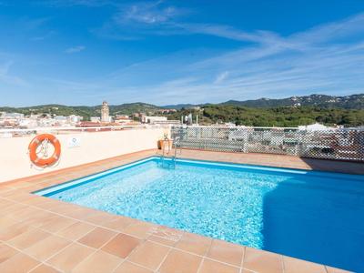 Piscina clara con azulejos de terracota en la azotea con vistas a la ciudad y colinas.