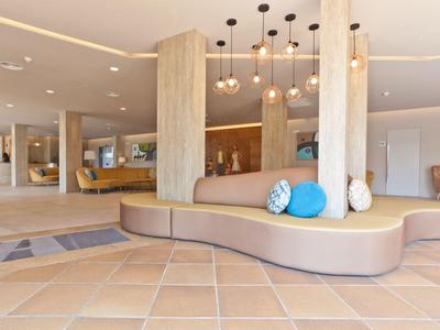 Heller Hotel-Lobby-Bereich mit modernen Sitzgelegenheiten und hängenden Kugelleuchten.