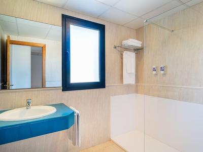 Modernes Badezimmer mit Waschbecken, großem Fenster und Ablageflächen für Handtücher.