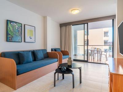 Moderner Hotelzimmerbereich mit Sofa, Tisch und Balkon mit Blick auf andere Gebäude.