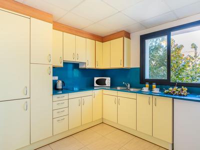 Moderne Küche mit gelben Schränken, blauer Arbeitsplatte und Fenster mit Blick ins Grüne.