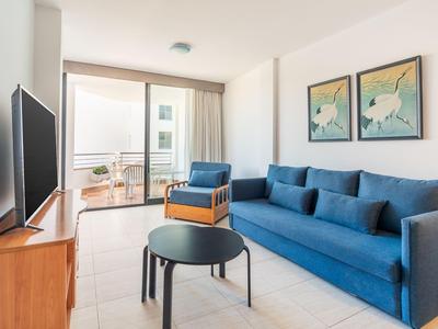 Moderner Hotelzimmer mit blauem Sofa, kleinem Tisch und Zugang zu Balkon mit Blick.