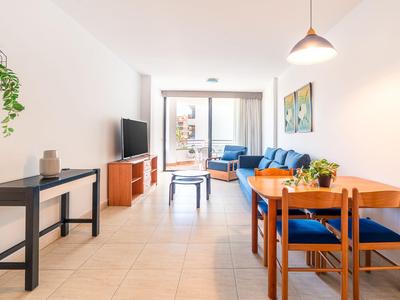 Helles Wohnzimmer mit Esstisch, Sofa und Zugang zu Balkon in einer modernen Ferienwohnung.