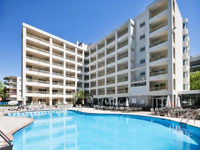 Large hotel with a clear blue pool and sunny sky