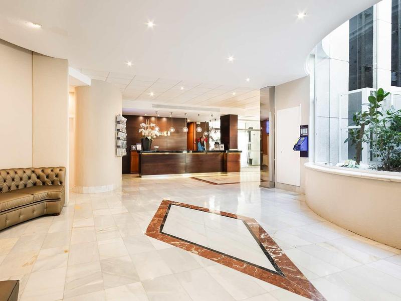 Spacious hotel lobby with marble floor, reception desk, and seating area.