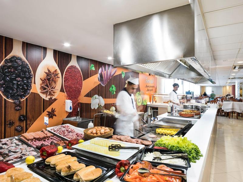 Bufet s velkým výběrem čerstvých jídel v moderní restauraci s barevnými nástěnnými dekoracemi.