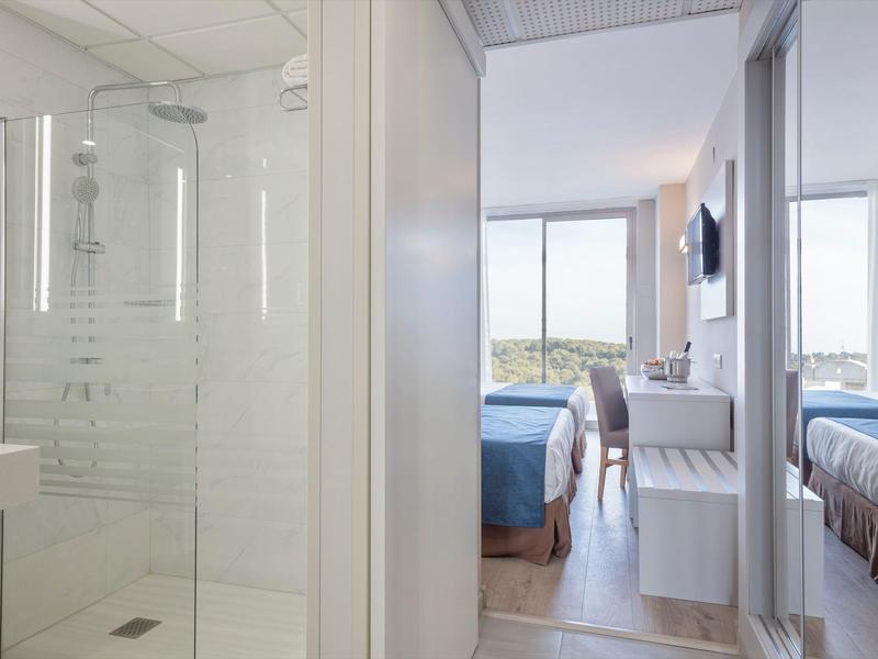 Hotelový pokoj s moderní koupelnou, dvěma postelemi a velkými okny s výhledem.